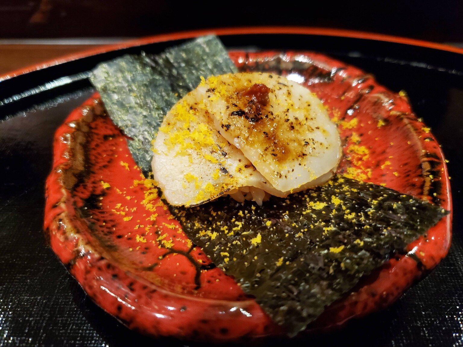 Torched nigiri on a red lacquer plate